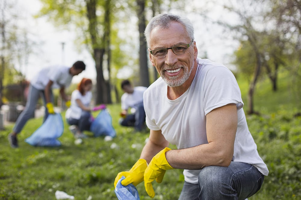 man volunteering to clean up trash in park as part of non-profit effort