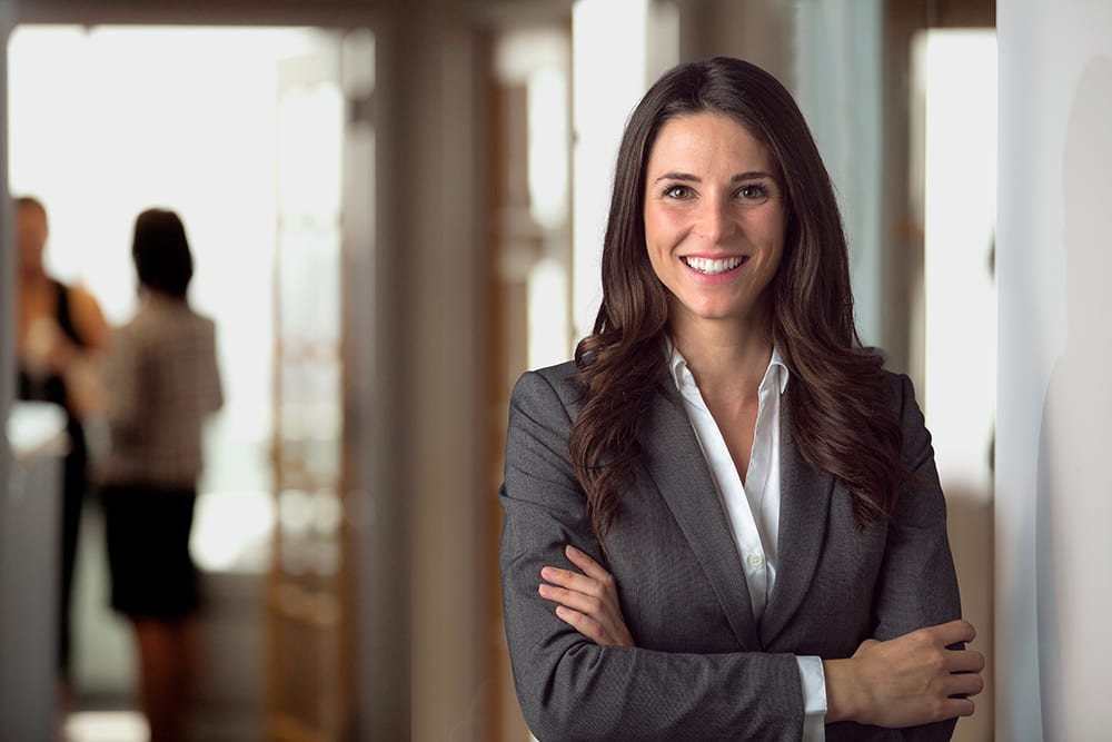 business woman leaning against office wall